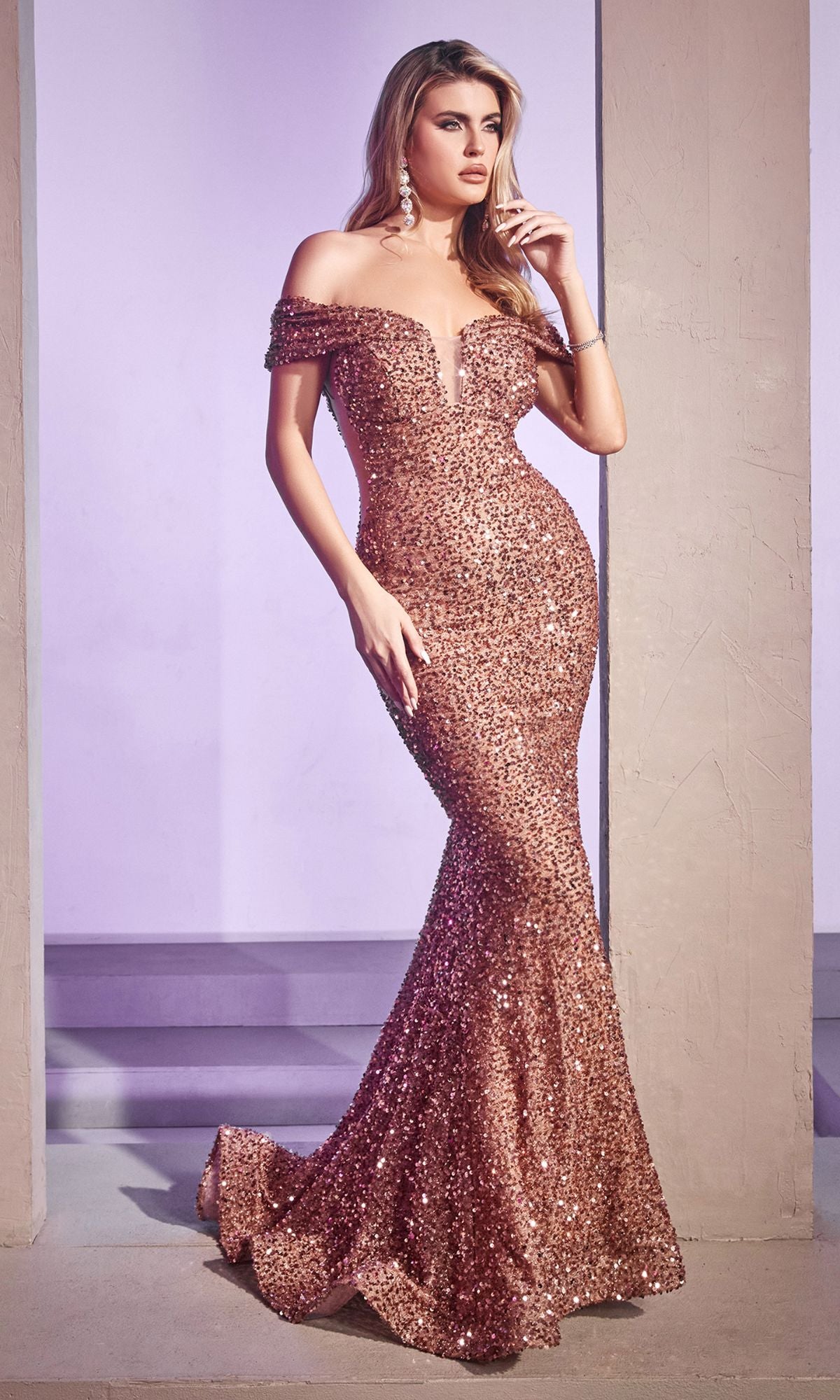 A woman models the CD975 Off-the-Shoulder Long Sequin Prom Dress in rose gold, standing between two indoor columns.